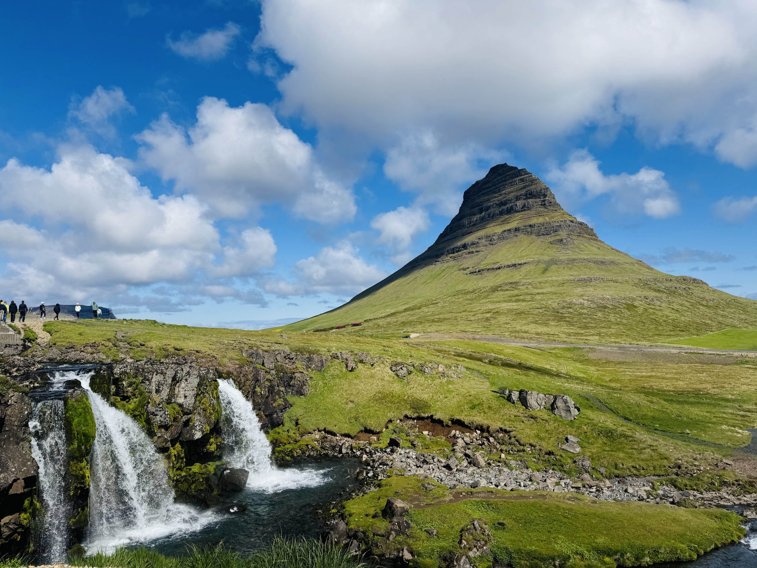 Scenic view of Grundarfjörður village with a waterfall cascading down lush green hills in western Iceland